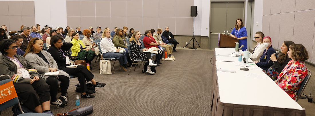 A conference panel speaking to a full audience